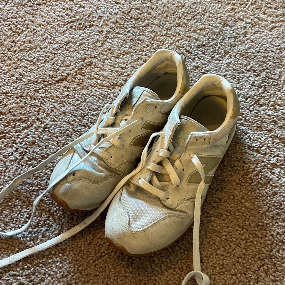 Well worn Gold J. crew new balance sneakers. Hold on top of right shoe.